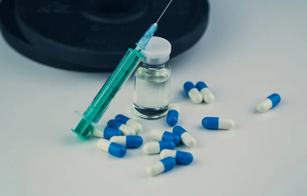 Dambıllar, iğneli şırınga, haplar ve steroidli şişe. Spor konseptinde yasadışı doping