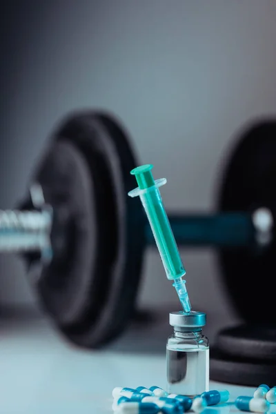 dumbbells, syringe with needle, vial and pills with steroids. illegal doping in sport concept