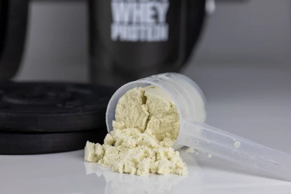 dumbbell and whey powder in scoop.  loss weigh or build muscle.