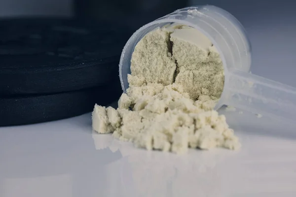 whey powder in scoop and dumbbell. loss weigh or build muscle.