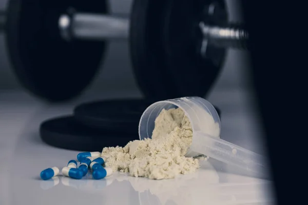 Dambıl, iğneli şırınga, haplar ve steroidli şişe ve kepçeli süt tozu. Spor konseptinde yasadışı doping. kilo vermek ya da kas yapmak.