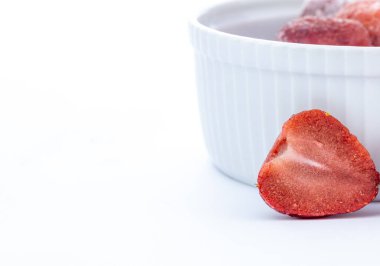 Beyaz arkaplandaki beyaz seramik kasede donmuş çilekler. 