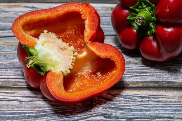 Stock image half and whole of red bell pepper isolated on wooden background.