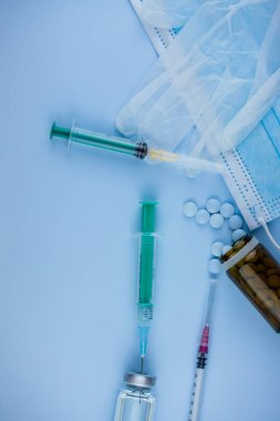 Beyaz koruyucu eldiven, tıbbi maske, iğneli şırınga, aşı şişesi ve haplar. Spor konseptinde yasadışı doping, grip aşısı, uyuşturucu bağımlısı, ıslak tıp. tıbbi öge arkaplanı