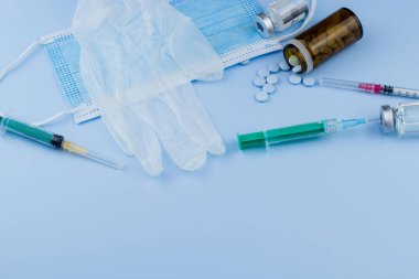Beyaz koruyucu eldiven, tıbbi maske, iğneli şırınga, aşı şişesi ve haplar. Spor konseptinde yasadışı doping, grip aşısı, uyuşturucu bağımlısı, ıslak tıp. tıbbi öge arkaplanı