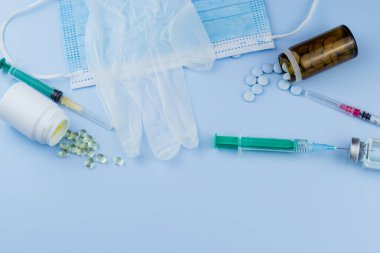 Beyaz koruyucu eldiven, tıbbi maske, iğneli şırınga, aşı şişesi ve haplar. Spor konseptinde yasadışı doping, grip aşısı, uyuşturucu bağımlısı, ıslak tıp. tıbbi öge arkaplanı
