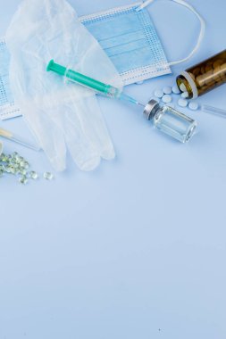 Beyaz koruyucu eldiven, tıbbi maske, iğneli şırınga, aşı şişesi ve haplar. Spor konseptinde yasadışı doping, grip aşısı, uyuşturucu bağımlısı, ıslak tıp. tıbbi öge arkaplanı
