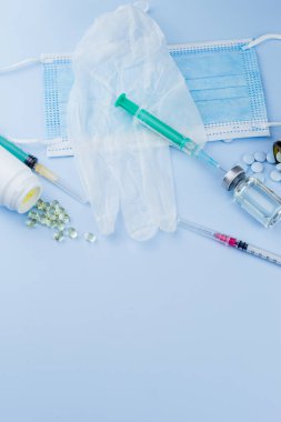 Beyaz koruyucu eldiven, tıbbi maske, iğneli şırınga, aşı şişesi ve haplar. Spor konseptinde yasadışı doping, grip aşısı, uyuşturucu bağımlısı, ıslak tıp. tıbbi öge arkaplanı