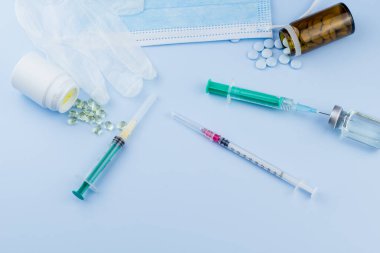 Beyaz koruyucu eldiven, tıbbi maske, iğneli şırınga, aşı şişesi ve haplar. Spor konseptinde yasadışı doping, grip aşısı, uyuşturucu bağımlısı, ıslak tıp. tıbbi öge arkaplanı