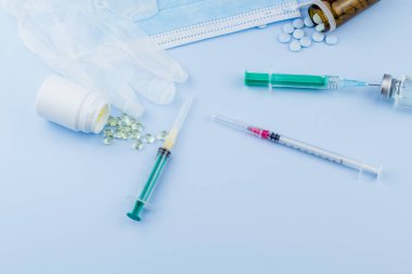 Beyaz koruyucu eldiven, tıbbi maske, iğneli şırınga, aşı şişesi ve haplar. Spor konseptinde yasadışı doping, grip aşısı, uyuşturucu bağımlısı, ıslak tıp. tıbbi öge arkaplanı