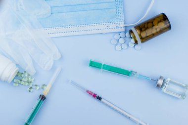 Beyaz koruyucu eldiven, tıbbi maske, iğneli şırınga, aşı şişesi ve haplar. Spor konseptinde yasadışı doping, grip aşısı, uyuşturucu bağımlısı, ıslak tıp. tıbbi öge arkaplanı