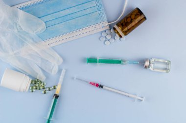 Beyaz koruyucu eldiven, tıbbi maske, iğneli şırınga, aşı şişesi ve haplar. Spor konseptinde yasadışı doping, grip aşısı, uyuşturucu bağımlısı, ıslak tıp. tıbbi öge arkaplanı