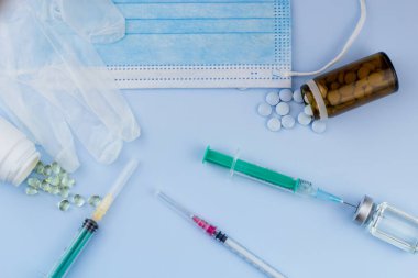 Beyaz koruyucu eldiven, tıbbi maske, iğneli şırınga, aşı şişesi ve haplar. Spor konseptinde yasadışı doping, grip aşısı, uyuşturucu bağımlısı, ıslak tıp. tıbbi öge arkaplanı