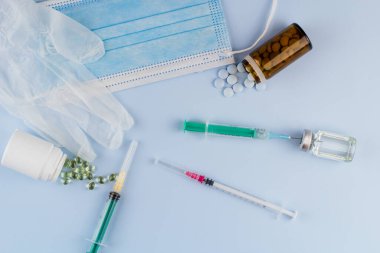 Beyaz koruyucu eldiven, tıbbi maske, iğneli şırınga, aşı şişesi ve haplar. Spor konseptinde yasadışı doping, grip aşısı, uyuşturucu bağımlısı, ıslak tıp. tıbbi öge arkaplanı
