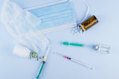 Beyaz koruyucu eldiven, tıbbi maske, iğneli şırınga, aşı şişesi ve haplar. Spor konseptinde yasadışı doping, grip aşısı, uyuşturucu bağımlısı, ıslak tıp. tıbbi öge arkaplanı