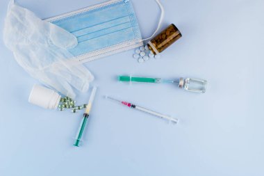 Beyaz koruyucu eldiven, tıbbi maske, iğneli şırınga, aşı şişesi ve haplar. Spor konseptinde yasadışı doping, grip aşısı, uyuşturucu bağımlısı, ıslak tıp. tıbbi öge arkaplanı