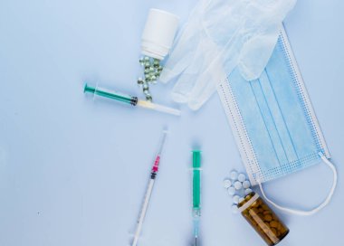 Beyaz koruyucu eldiven, tıbbi maske, iğneli şırınga, aşı şişesi ve haplar. Spor konseptinde yasadışı doping, grip aşısı, uyuşturucu bağımlısı, ıslak tıp. tıbbi öge arkaplanı