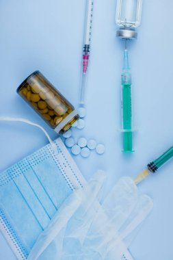 Beyaz koruyucu eldiven, tıbbi maske, iğneli şırınga, aşı şişesi ve haplar. Spor konseptinde yasadışı doping, grip aşısı, uyuşturucu bağımlısı, ıslak tıp. tıbbi öge arkaplanı