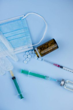 Beyaz koruyucu eldiven, tıbbi maske, iğneli şırınga, aşı şişesi ve haplar. Spor konseptinde yasadışı doping, grip aşısı, uyuşturucu bağımlısı, ıslak tıp. tıbbi öge arkaplanı