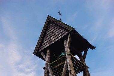 Scandinavian wooden church belfry bell tower in pine and spruce wood with cross against blue sky as religion and religious christian concept in Stockholm, Sweden