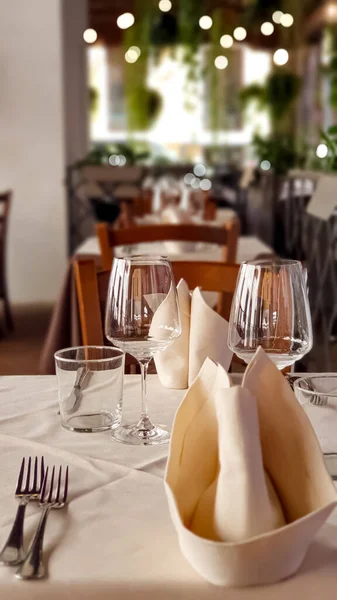 A prepared table in a fancy restaurant with wine glasses, napkins and cutlery