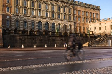 Stockholm Kraliyet Sarayı önünde bisiklet yolunda bisiklet süren banliyö bisikletçileri. Bir sonbahar sabahı hareket bulanıklığı ile.