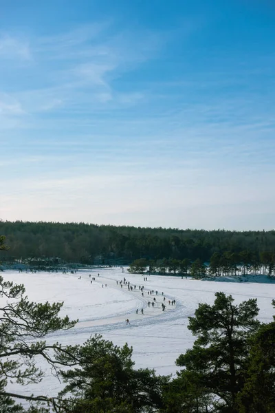 People ice skating on a frozen lake in Sweden on sunny day