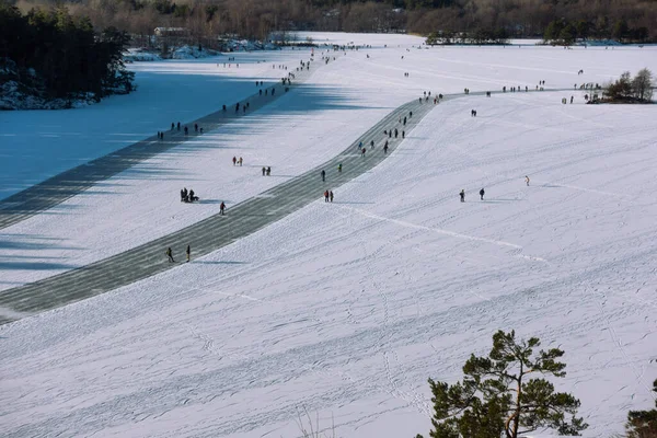 Aerial view of people ice skating on a frozen lake in Hellasgarden in Sweden on sunny day