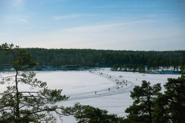 Crowd of people ice skating on a frozen lake in Sweden on sunny day