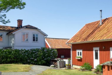 Kırsal ve pitoresk İsveç köyünde sakin bir yerleşim yeri. Yazın beyaz köşeli, mavi gökyüzü olan kırmızı bir ev.