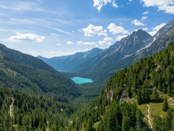 Passo Stalle 'den (Staller Geçidi) yeşil çam ormanlı bir Dolomite dağ vadisinde görülen alp gölü Lago di Anterselva (Antholzer See) hava manzarası 