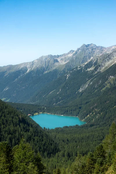 Passo Stalle 'den (Staller Pass) yeşil çam ormanlı bir Dolomite dağ vadisinde görülen turkuaz dağ gölü Lago di Anterselva' nın (Antholzer See) havadan görünüşü