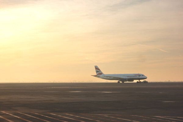 Venice, Italy - 23 December 2023: British Airways flight taxiing to the runway of airport in warm morning fog in winter with clouds in the sky above