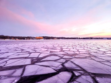 İsveç 'in başkenti Stockholm' de mor ve pembe gökyüzü ve gökyüzünde bulutlar olan İskandinav sabahının erken saatlerinde kış mevsiminde denizde buz örtüleri.