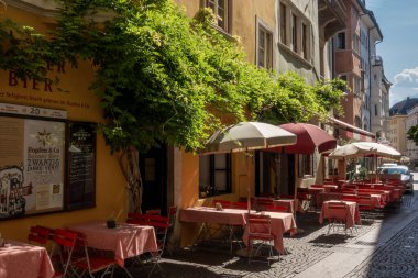 Bolzano, İtalya - 13 Ağustos 2023: Bolzano 'da rahat bir restoran olan Hopfen and Co' nun sandalyeleri ve masalarıyla yaz aylarında küçük bir Alp kasabasında sakin bir tyrolean caddesi