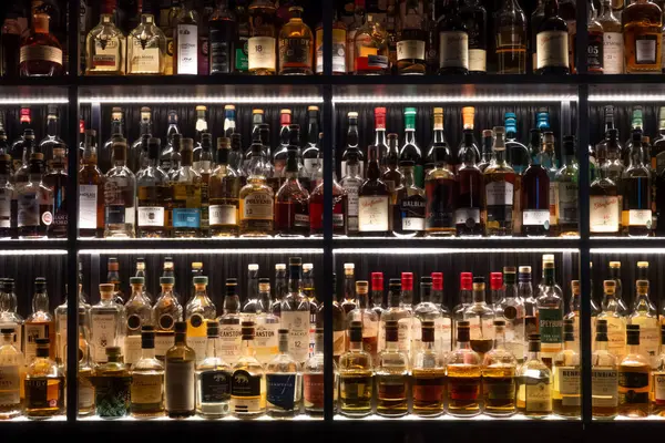 stock image Inverness, Scotland - 12 August 2024: shelves of Scottish whiskey bottles in modern dark bar or pub