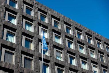 Stockholm, İsveç - 19 Nisan 2023: İsveç merkez bankası Sveriges Riksbank 'ın karanlık taş cephesi ve bankanın mavi bayrağı