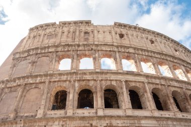 Roma, İtalya 'daki antik Roma Kolezyumu' nun dış cephesi ve dış cephesi güneşli bir günde beyaz bulutlar ve mavi gökyüzü