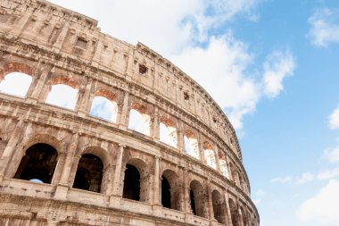 Roma, İtalya 'daki antik Roma Kolezyumu' nun dış cephesi ve dış cephesi güneşli bir günde beyaz bulutlar ve mavi gökyüzü