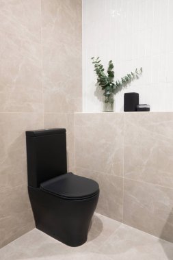 Lüks bir iç mekan konsepti için açık bej ve beyaz seramik seramik seramik kaplamalı siyah klozet kapağı olan zarif bir banyo tasarımı.