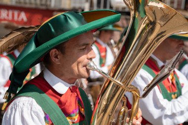 Santa Cristina (BZ), Italy - 20 July 2025: Man playing a baritone horn in a folk marching band wearing a traditional south tyrolean tracht and lederhosen during a procession festival in Val Gardena
