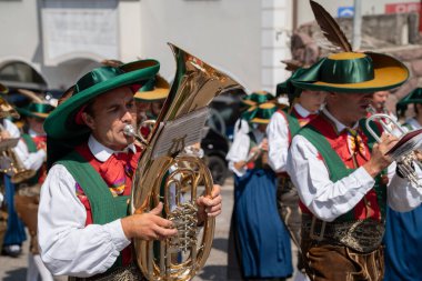 Santa Cristina (BZ), Italy - 20 July 2025: Man playing a baritone horn in a folk marching band wearing a traditional south tyrolean tracht and lederhosen during a procession festival in Val Gardena