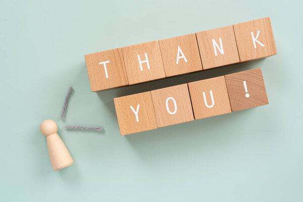 Thank you; Wooden blocks with "THANK YOU!" text of concept and a human toy.