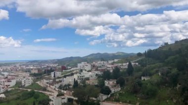 Şehri tam olarak gören çarpıcı bir şehir manzarası. Şehir, gökdelenleri, evleri ve nehri olan bir renk kargaşası. Sokaklar hareketle dolup taşıyor ve insanlar günlük yaşamlarını sürdürüyorlar.