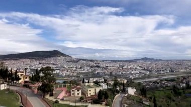 Ufukta bulutlar görünen manzaralı şehir manzaraları. Şehir manzaraları rengarenk, gökdelenleri, binaları var. Bulutlar ince ve beyaz ve yavaşça gökyüzünde sürükleniyorlar.