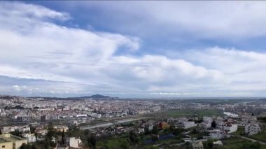 Ufukta güzel şehir manzaraları ve bulutların görüntüsü. Görüntüler, yüksek gökdelenleri, dolambaçlı nehirleri ve yemyeşil parklarıyla bu kentsel manzaraların çarpıcı güzelliğini yakalıyor. Bulutlar biraz drama ve ihtişam katar. 