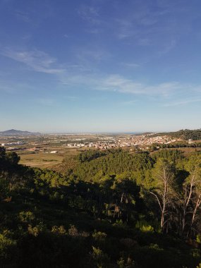 Doğanın manzarası - bir barış ve sükunet sembolü - doğanın çarpıcı bir manzarası, güneş ışığıyla yıkanmış. Görüntü yemyeşil ağaçlarla, yuvarlanan tepelerle ve mavi gökyüzüyle dolu. Sahne huzurlu ve huzurlu.