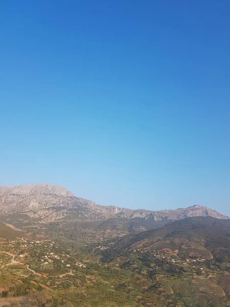 Kırsal ve dönümlü dağlık bir tepe, ufka kadar uzanan yemyeşil kırsalları ve tarlaları olan dağlık bir tepe. Tepe ağaçlarla kaplı ve kırsal bölge çiftlik evleri ve ahırlarla dolu.