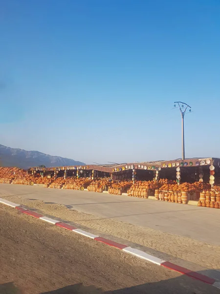 Yol kenarındaki çömlekçilerde renkli bir sergi eşyası ve tagin. Toprak eşyalar kırmızı, sarı, mavi ve yeşil olmak üzere çeşitli renklerdir. Taginler de çeşitli renklerdedir.