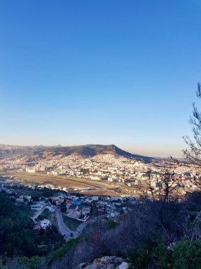 Granada 'nın ikizi olan Tetouan şehrinin uzaktan görünüşü, Granada ikizinin gölgeler ve güneş ışığının dağlar arasındaki ufukta buluştuğu engin şehirde battığı yerde.
